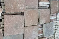 Tomettes carrées aux nuances grisées et rosées disposées à plat sur des carreaux rangés sur chant.